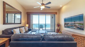 The living groom, with its twin leather sofas, TV, and sliding doors that open onto the balcony.