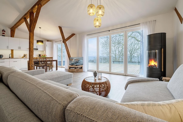Offenes Wohnzimmer mit Couch, Meerblick, Ofen und Essbereich