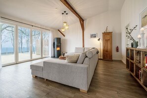 Offenes Wohnzimmer mit Couch, Meerblick, Ofen und Essbereich