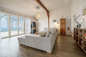 Offenes Wohnzimmer mit Couch, Meerblick, Ofen und Essbereich
