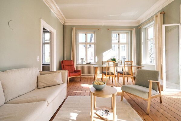 Wohnzimmer mit Couch, Esstisch und TV