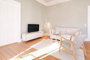 Wohnzimmer mit Couch, Esstisch und TV