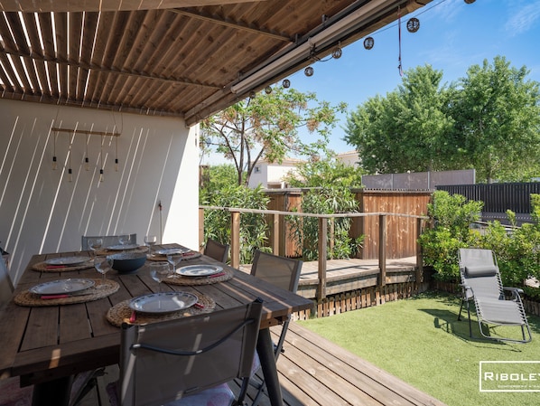 Terrasse ouverte sur le jardin avec barbecue et salons de jardin