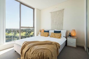 The queen-sized bedroom boasts floor-to-ceiling windows capturing beautiful natural light.