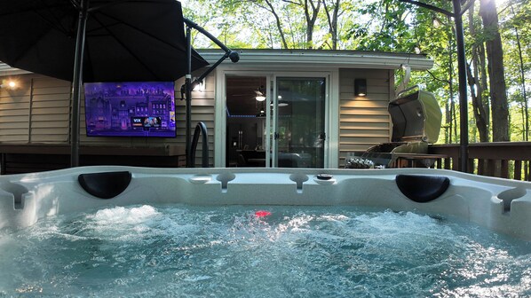 From the warmth of your private hot tub, take in views of the deck’s cozy seating, bar, and outdoor TV—all while the gentle sounds of the nearby brook complete the perfect moment.