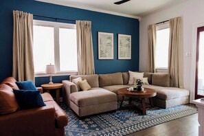 Settle into this inviting living space featuring a comfy sectional, wall-mounted Smart TV, and electric fireplace. Bright natural light and a warm entryway create the perfect retreat after exploring the city.