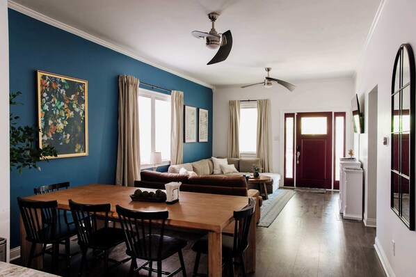 Warm and welcoming open-concept living and dining space with chic decor, plenty of natural light, and vibrant accent walls — ideal for shared meals, game nights, or unwinding after a day in downtown Indy!