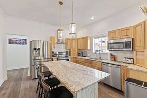 This home boasts a modern, fully equipped kitchen with sleek stainless steel appliances. The light countertops and minimalist cabinetry create a clean open feel, while the breakfast bar with stools provide a casual dining option.