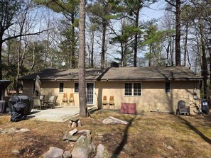 Backyard with patio, large table with umbrella, gas grill, charcoal grill, fire pit.