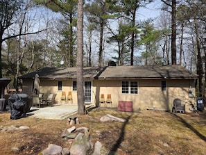 Backyard with patio, large table with umbrella, gas grill, charcoal grill, fire pit.