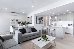 The living area seamlessly connects to the open-plan kitchen and dining space, complete with ceiling fans and an air conditioning split system for your comfort.