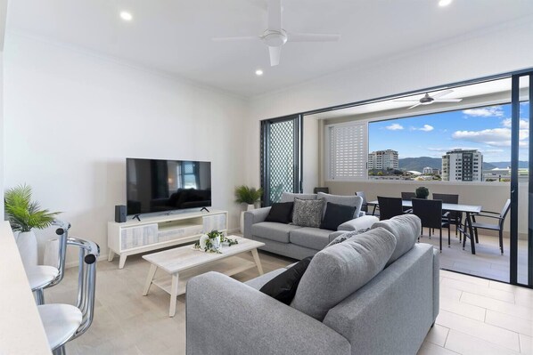 The light-filled living area offers two cosy sofas to settle in with a movie, while glass doors create a seamless flow out to the balcony.