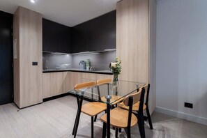 Experience modern living in this stylish kitchen, featuring sleek cabinetry and a cozy dining area perfect for meals and gatherings.