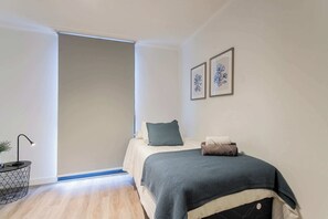 Cozy single bedroom with modern decor and soft lighting, perfect for a restful night's sleep.