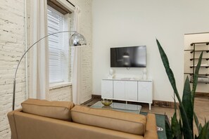 Cozy lounge with modern decor, smart TV, and vintage brick charm.