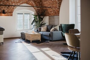 Charming lounge corner with sunlit windows and comfortable seating beneath original brick arches.