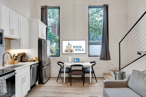 This sleek kitchen and dining space features stainless steel appliances, tall windows, and a cozy seating area. Ideal for guests who love to cook or enjoy takeout from nearby local gems.