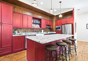 This vibrant, fully stocked kitchen is ready for all your cooking adventures, featuring bold cabinetry, modern appliances, and plenty of space to gather around.