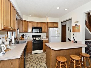 Fully equipped kitchen featuring wooden cabinetry, modern appliances, and a breakfast bar.