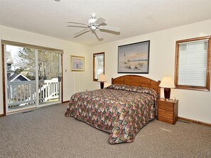 Comfortable bedroom with a queen bed, private balcony access, and large windows offering plenty of sunlight and a refreshing coastal breeze.