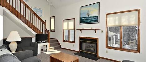 Spacious and inviting living area with high ceilings, a cozy fireplace, and ample natural light—perfect for relaxing after a day at the beach.