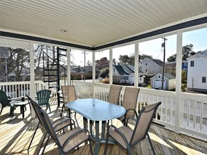 Screened-in porch with a dining set, offering the perfect spot to enjoy meals outdoors while soaking in the coastal atmosphere.