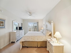 This serene master bedroom features coastal-inspired decor, providing a relaxing retreat with access to a private balcony view.