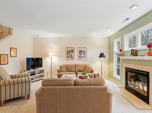 Embrace comfort and warmth in the living room, highlighted by large windows and a charming fireplace, creating an inviting space for relaxation and leisure in this elegant townhome.