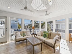 The inviting three-season room is an ideal spot for relaxation, showcasing modern furnishings and plenty of natural light.