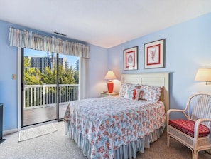 Rest easy in the beautifully decorated master bedroom featuring a queen bed and sliding glass doors leading to the deck, offering a perfect setting to start and end your beach days.
