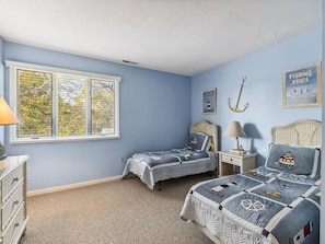 Embrace coastal charm in this serene bedroom, featuring cozy twin beds adorned with nautical décor, perfect for restful nights after sun-filled beach days.