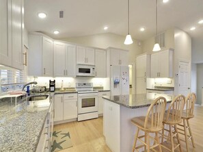 The modern kitchen shines with updated appliances and ample space, perfect for entertaining after a day at the beach or enjoying ocean views.