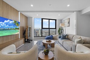 A wide angle of this spacious living room, comfortable lounge chairs with sky high cityscape views