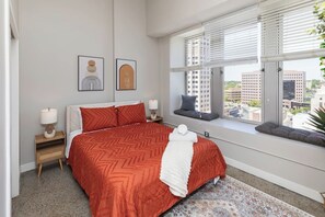 Bedroom 1 w/ queen bed, Roku smart TV, nightstand chargers, closet and amazing downtown view!