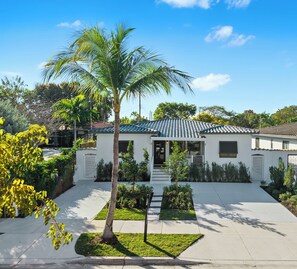 Welcome to your private Miami oasis with lush landscaping and a sleek facade.