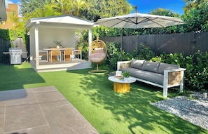 Enjoy the lush backyard oasis with a couch, umbrella, and swing chair.