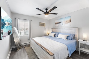 Spacious king bed with blackout curtains, ceiling fan, and smart TV.