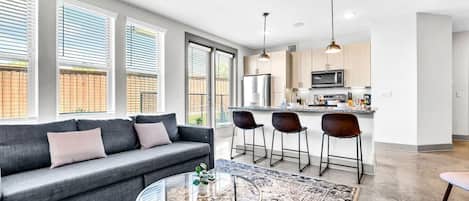 The living room’s plush seating beckons you to sink in and relax, surrounded by light and airy decor.