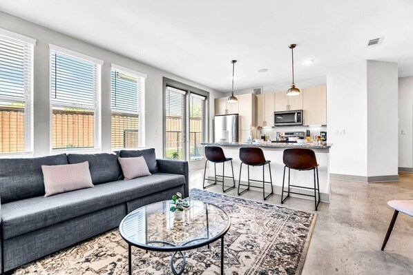 The living room’s plush seating beckons you to sink in and relax, surrounded by light and airy decor.