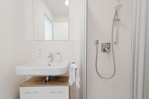 Hochwertiges Bad mit Dusche, Waschbecken und praktischen Ablagen.