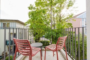 Gemütlicher Balkon mit Sitzgelegenheit und Ausblick auf Bäume.