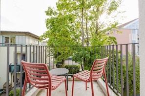 Gemütlicher Balkon mit Sitzgelegenheit und Ausblick auf Bäume.