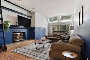 Spacious living room with plenty of natural light, comfy couches, large smart TV and fireplace