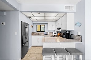 Enjoy a full kitchen with stainless steel appliances and bar seating for three—perfect for casual meals or morning coffee.