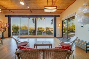 Large bonus space/yoga studio (just off the living room )with cozy seating, desk, and floor-to-ceiling windows providing stunning views of the property's beautifully landscaped backyard