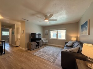 Open concept Living and Dining Area. Features a sofa-bed, ceiling fan, and a TV 