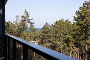 Terrace view – peaceful greenery and a glimpse of the sea just beyond the trees.