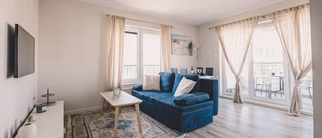 Spacious living room with a comfortable sofa bed and large TV – the perfect family retreat after a day on the beach in Ustronie Morskie.