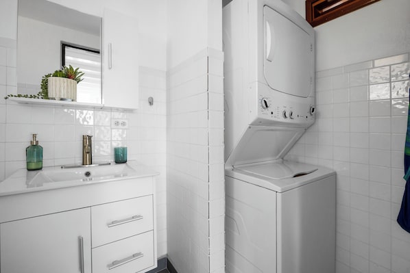 Refresh in the modern bathroom with a spacious shower, stylish vanity, and built-in laundry area – great for extended stays or packing light.