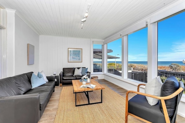 Sink into leather sofas in the first living room as the sun sets over the sea, framed by panoramic windows that bring the outdoors inside.